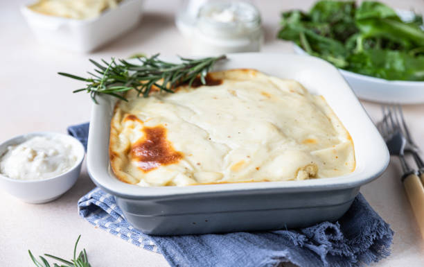 Cauliflower gratin with chicken and bechamel sauce decorated with rosemary in a baking dish. Savory casserole. stock photo