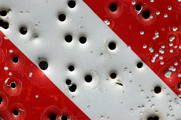 Caution: bullet holes Bullet holes of various calibers in a caution sign near a firing range. nra stock pictures, royalty-free photos & images