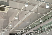 istock Ceiling with bright lights in a modern warehouse, shopping center building, office or other commercial real estate object. Directional LED lights on rails under the ceiling 1344833299