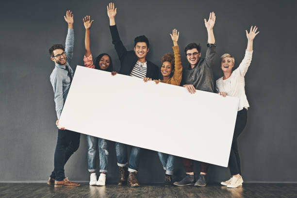 Celebrating your display Studio shot of a diverse group of people holding up a placard against a grey background free sign up stock pictures, royalty-free photos & images