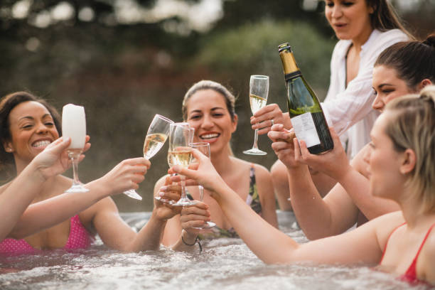 Celebratory Toast in the Hot Tub Small group of female friends socialising and relaxing in the hot tub on a weekend away. They are celebrating with a glass of champagne. county durham england stock pictures, royalty-free photos & images