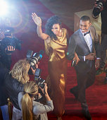 istock Celebrity couple waving and being photographed by paparazzi photographers at red carpet event 559536999