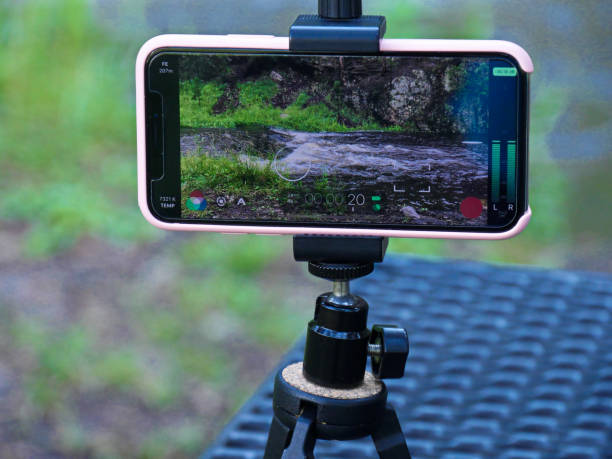 A cellular phone on a tripod filming a video of a flowing river stock photo