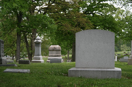 close up on a tombstone ready for your copy. Other tombstones and dreary cemetary in background.