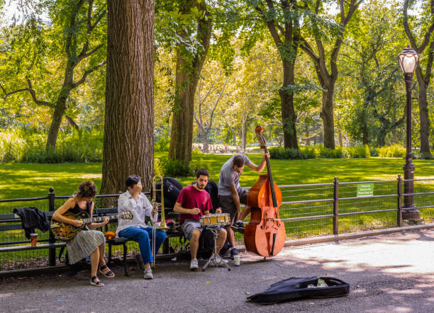 Central Park, in summer, with street musicians on a bench, and a lamppost stock photo