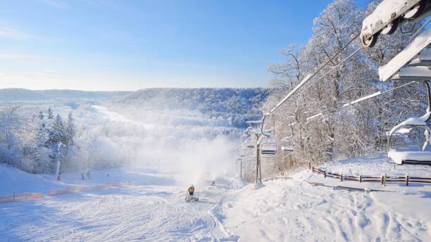 Chair lift for skiing covered in snow and hoarfrost with a skiing slope view and snow cannons stock photo