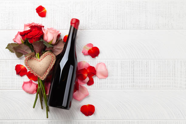 Champagne bottle and rose flowers Champagne bottle and rose flowers. Valentines day greeting card with heart decor and space for your greetings. Top view flat lay happy birthday wine bottle stock pictures, royalty-free photos & images