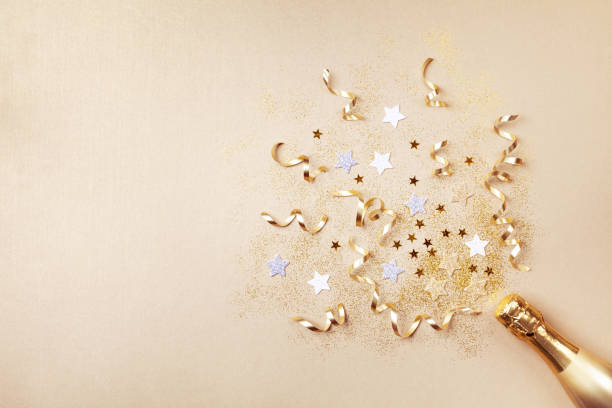champagne bottle with confetti stars, glitter and party streamers on golden background. christmas, birthday or wedding concept. flat lay concept. - fogo de artifício dourado imagens e fotografias de stock