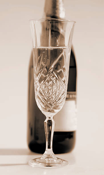 Crystal Glass with Wine or Champagne bottle in backgroud.  Set up on white  shooting table with shadow on left side.   