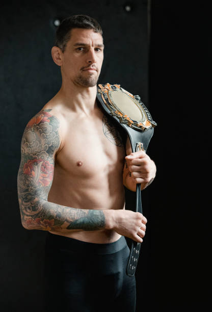 Champion MMA Fighter MMA fighter is posing with his champion belt in front of a dark wall. sports champion stock pictures, royalty-free photos & images