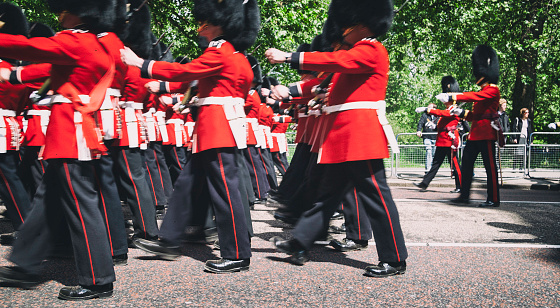 London England - May 21, 2010: Soldiers wearing the red ceremonial uniforms march in perfect step away from Buckingham Palace, the London residence of the British Monarch. This is the famous Changing of the Guard.