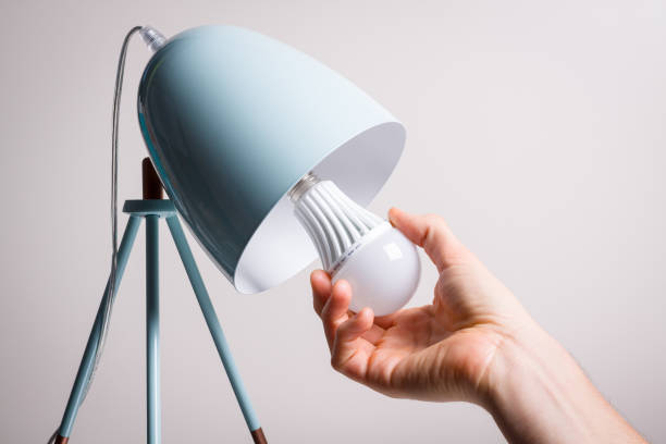 Changing the bulb for led bulb in table lamp in turquoise colours. stock photo