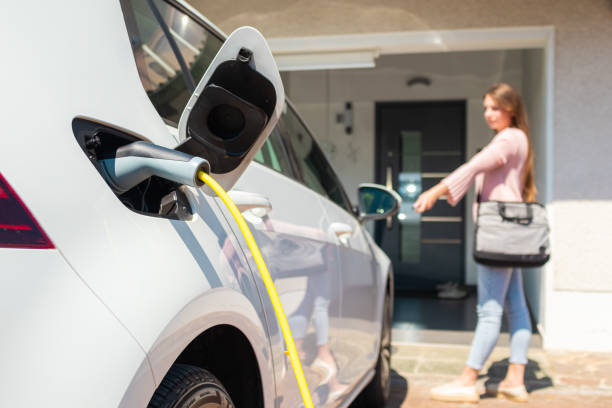 EV Charger station at home Woman charging electric car at home with cable. electric vehicle charging station photos stock pictures, royalty-free photos & images