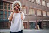 One woman, modern mature lady with gray hair, talking on mobile phone.