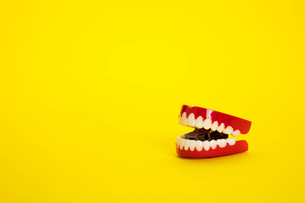 Chattering teeth on yellow background stock photo