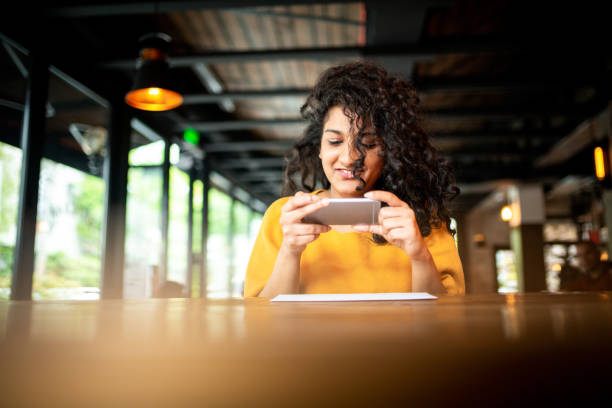 Check remote deposit capture at coffee shop Young Indian woman making a photo of a check at the bar culture of india photos stock pictures, royalty-free photos & images