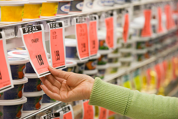 checking price of item in supermarket aisle - consumismo imagens e fotografias de stock