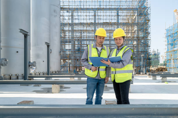 checking  report in  chemical plant Two male and female engineers are checking the report in the chemical plant oil refinery factory stock pictures, royalty-free photos & images
