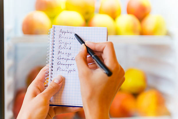 Checking shopping list. Close-up of woman checking shopping list with apples in the background shopping list stock pictures, royalty-free photos & images