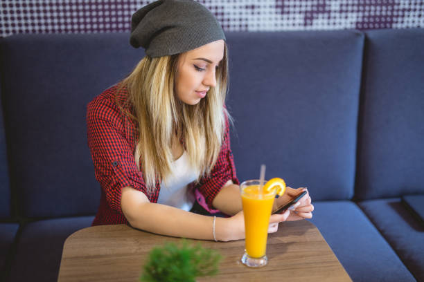 Checking social media The pretty teenage girl sitting at fast food restaurant / cafe. She is 20 years old and have beautiful blue eyes. She is relaxed and enjoying her coffee and surfing net. Portable DVD Player stock pictures, royalty-free photos & images