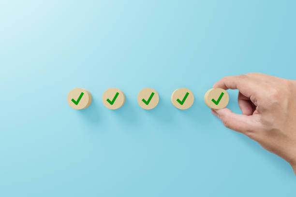Checklist and check mark concept. Check mark on wooden blocks on light blue background stock photo