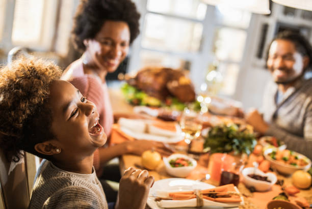alegre chica afroamericana con sus padres en la mesa de comedor. - family dinner fotografías e imágenes de stock