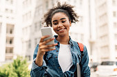 istock Cheerful African American Student Girl Using Mobile Phone Standing Outside 1342235356
