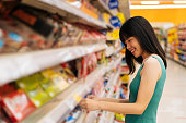 スーパーマーケットで食べ物を選ぶ陽気なアジアの女性