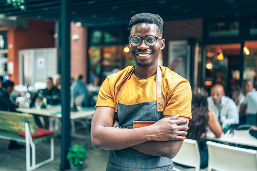 Portrait of young man, bartender. Coffee shop working in apron smiling at camera