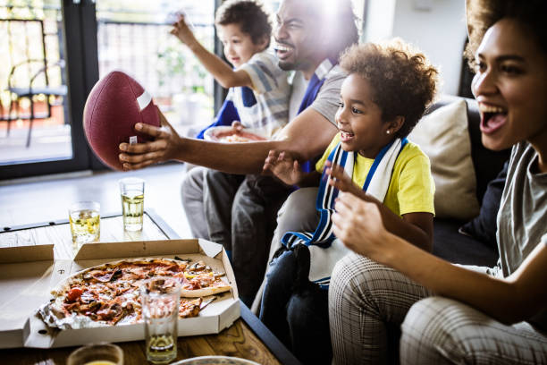 vrolijke zwarte familie juichen tijdens het kijken naar rugby wedstrijd op tv thuis. - kijken naar stockfoto's en -beelden
