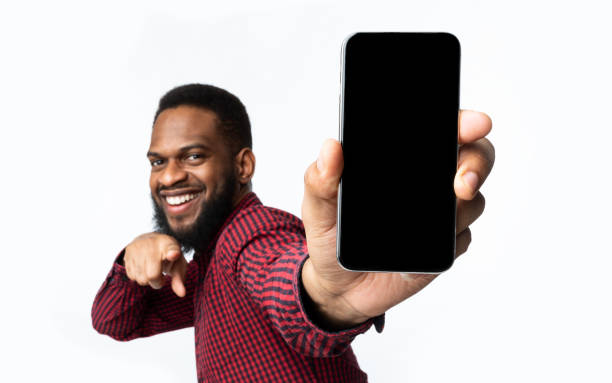 fröhliche schwarze kerl zeigt telefon bildschirm zu kamera, weißer hintergrund - man hand holding stock-fotos und bilder