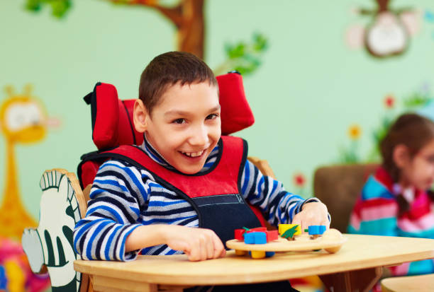 cheerful boy with disability at rehabilitation center for kids with special needs stock photo