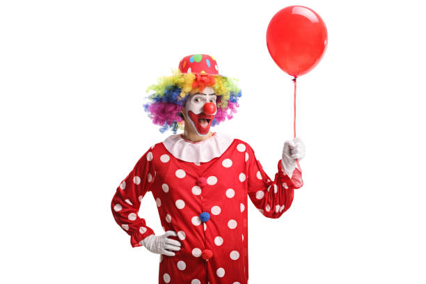 Cheerful clown holding a red balloon Cheerful clown holding a red balloon isolated on white background clown stock pictures, royalty-free photos & images
