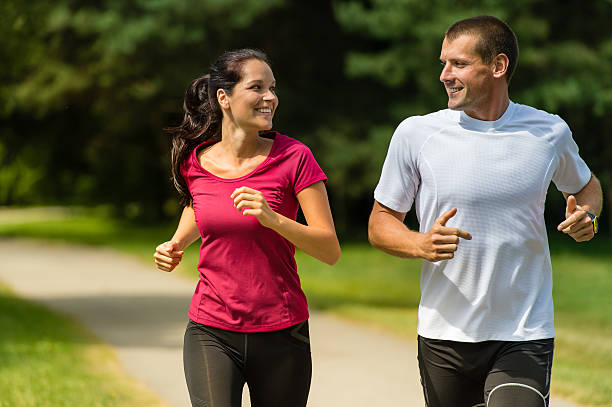 Cheerful couple running outdoors stock photo