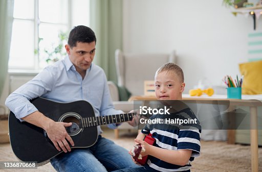 istock Cheerful down syndrome boy with father playing musical instruments, laughing. 1336870668