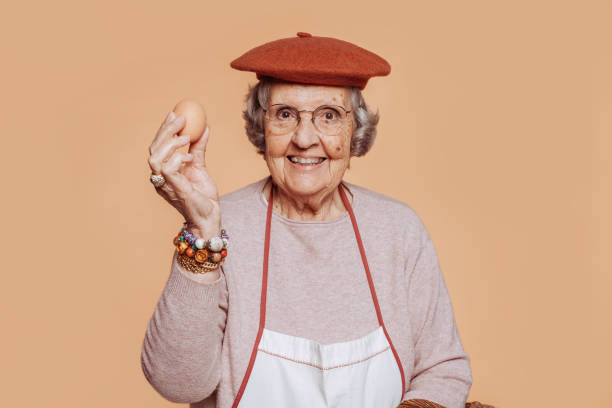 Cheerful elderly grandmother cook holding an egg stock photo