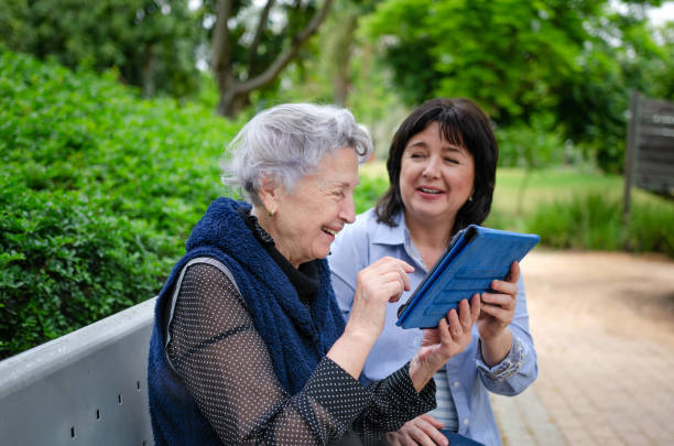 Cheerful elderly woman quickly studies to use the tablet to communicate in social networks stock photo
