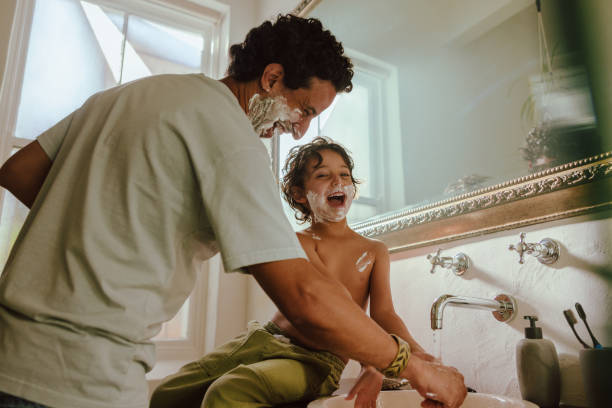 Cheerful father and son having fun with shaving foam stock photo