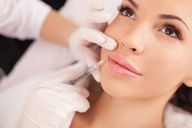 Cheerful healthy lady is visiting expert beautician Close up of hands of cosmetologist making botox injection in female lips. She is holding syringe. The young beautiful woman is receiving procedure with enjoyment human lips stock pictures, royalty-free photos & images