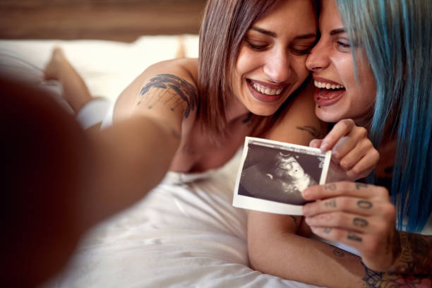 Cheerful homosexual female showing ultrasound image of future baby stock photo