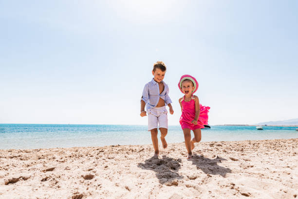 Cheerful kids having fun in summer day on the beach. stock photo