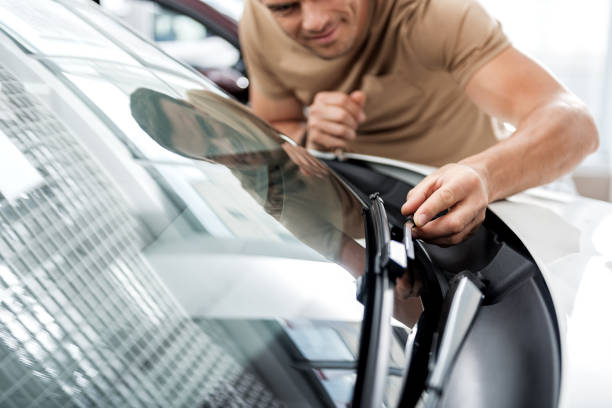 Cheerful male examining technical equipment of car Outgoing man straightening wipers in automobile. He standing near it. Adoration concept windshield wiper stock pictures, royalty-free photos & images