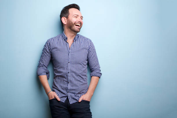 cheerful man with beard posing against blue wall stock photo