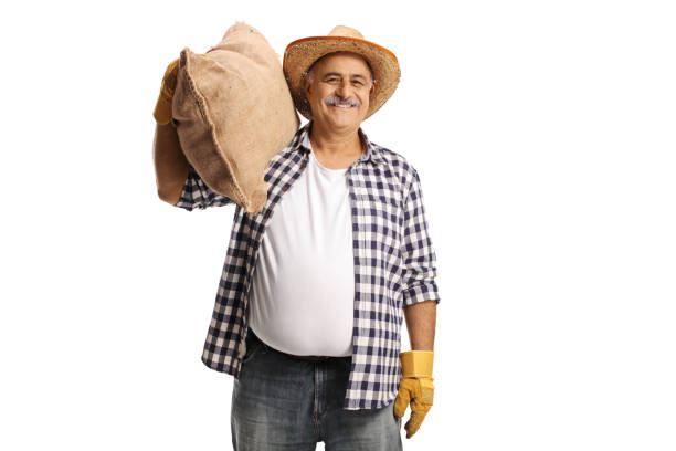 Cheerful mature farmer carrying a big burlap sack on his shoulder stock photo