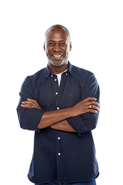 Cheerful mature man standing with his arms crossed against white stock photo
