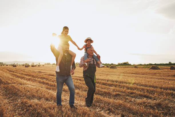 Cheerful multi-generational family having fun in a harvested wheat field stock photo