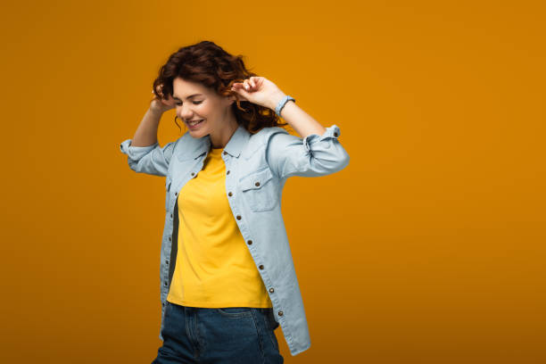 cheerful redhead woman plugging ears while standing on orange cheerful redhead woman plugging ears while standing on orange Fingers in Ears stock pictures, royalty-free photos & images