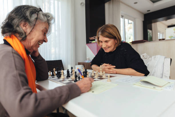 Cheerful senior woman playing chess Cheerful  senior woman playing chess roommate stock pictures, royalty-free photos & images