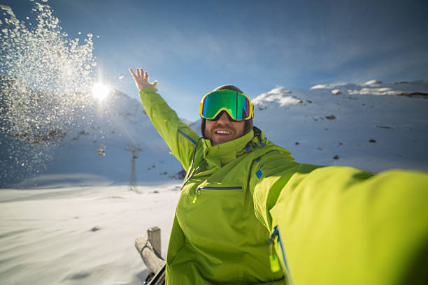 cheerful skier taking selfie on ski slopes throwing snow-sunset time - posing with ski stockfoto's en -beelden