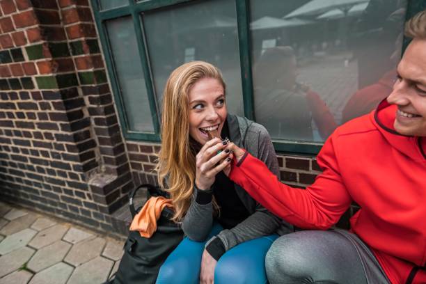 Cheerful sporty couple having pause on the sidewalk Young athletic couple sitting next to each other , preparing for run couple eating chocolate stock pictures, royalty-free photos & images